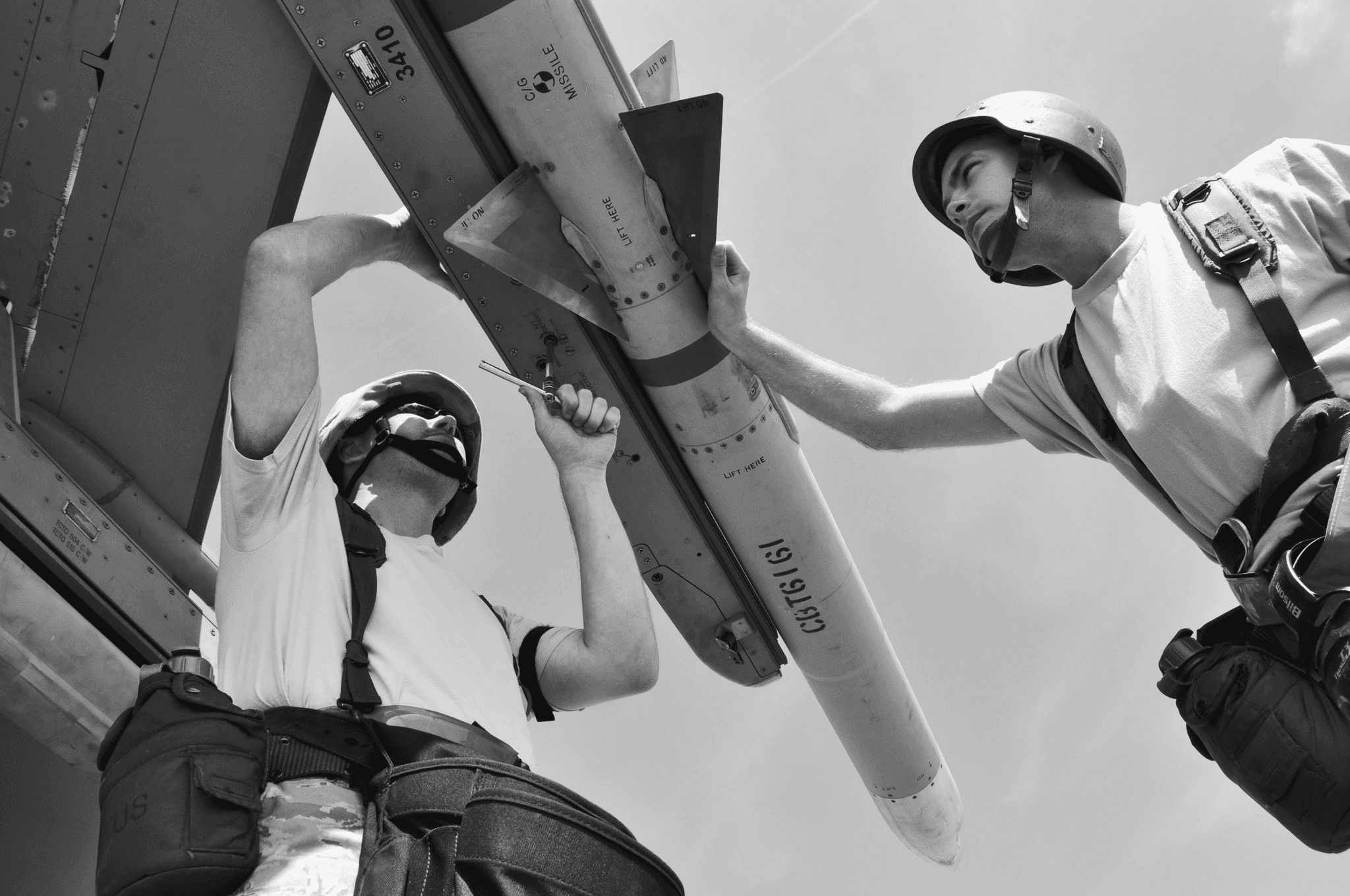 A couple of people in protective equipment work on a drone.